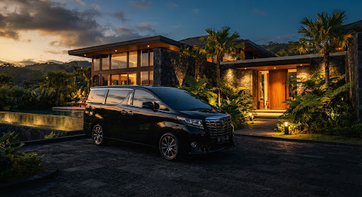 Toyota Alphard berwarna hitam berada di depan villa privat modern saat senja di Lombok